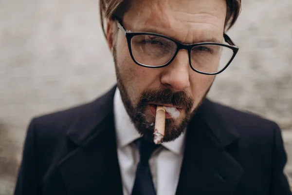 Entrepreneur in suit and eyewear smoking on street — Stock Photo, Image