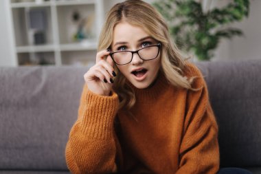 Kanepede oturan göz giysili, şaşırmış kadın.