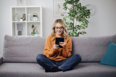 Kanepede tablet kullanan rahat kadın.