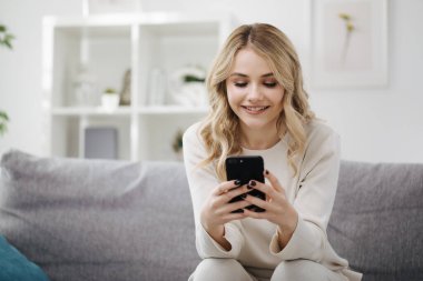 Evde akıllı telefon kullanan bir kadın.