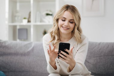 Kanepede oturan ve cep telefonu kullanan kadın.