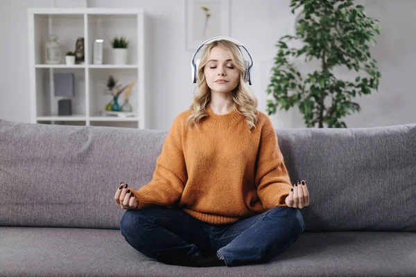 Kanepede kulaklıkla meditasyon yapan bir kadın. — Stok fotoğraf