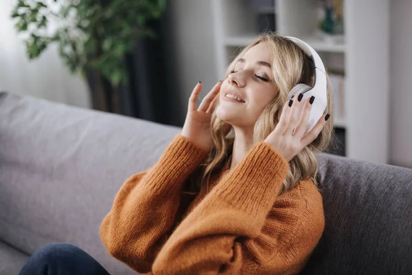 Mujer satisfecha disfrutando de la música en el sofá — Foto de Stock