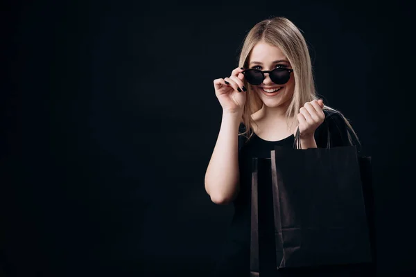 Жінка стоїть над чорним тлом з сумками — стокове фото
