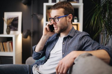 Kanepede konuşan genç adam.