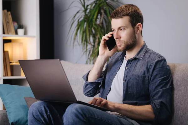 Homem usando smartphone e laptop em casa — Fotografia de Stock