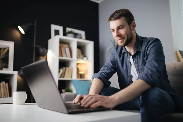 소파에서 노트북으로 타이핑하는 행복 한 남자 — 스톡 사진