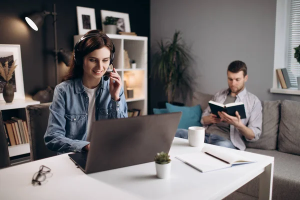 남자가 책읽는 동안 노트북으로 비디오 통화를 하는 여자 — 스톡 사진