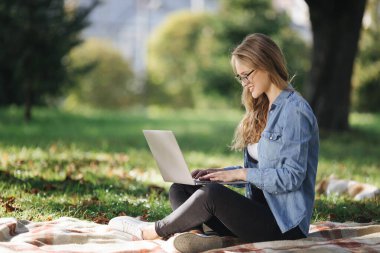 Parkta dizüstü bilgisayarda çalışan kadının yan görüntüsü