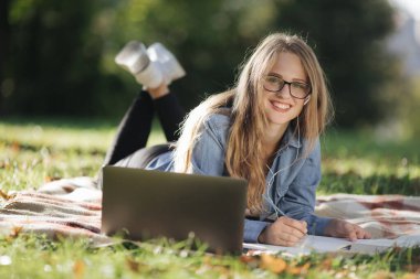 Parkta çalışmak için dizüstü bilgisayar kullanan güzel bir kadın.