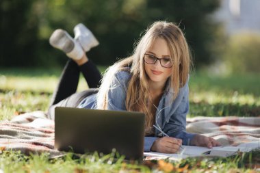 Doğada dizüstü bilgisayarla çalışan bir kadın.
