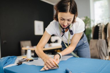 Dressmaker mavi kumaş üzerinde bir desen yapıyor