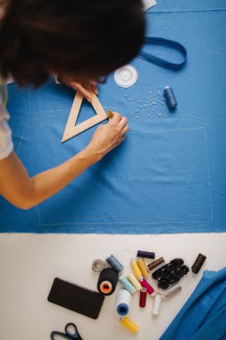 Atölyede mavi kumaşla çalışan odaklı tasarımcı