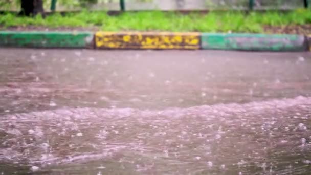 Κοντινές σταγόνες καλοκαιρινής ή φθινοπωρινής βροχής νερού πέφτουν στην άσφαλτο της πόλης και μετατρέπονται σε μια μεγάλη λακκούβα, πλημμυρίζοντας το δρόμο. Οι σταγόνες βροχής πέφτουν. αργή κίνηση, Στρατηγέ Πάλν. — Αρχείο Βίντεο