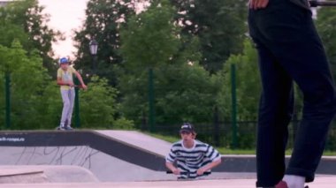 Rusya Moskova 2020. Çocuklar, gençler sonbaharda ekstrem spor sokak paten parkında kaykay ve scooter kullanıyor. yavaş çekim