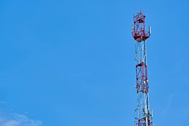 Mavi gökyüzüne karşı antenli iletişim kulesi.