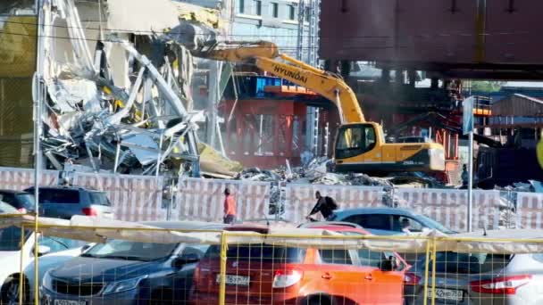 MOSCOW-jule 2020：一台挖掘机摧毁了一座商业建筑。附近的城市交通正在沿路行驶 — 图库视频影像