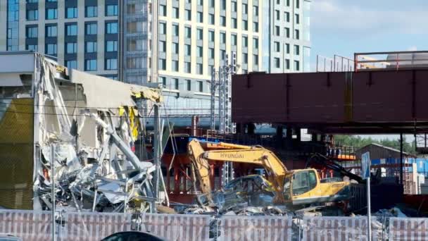 MOSCOU-jule 2020 : une excavatrice démolit un bâtiment commercial. la circulation urbaine à proximité se déplace le long de la route — Video