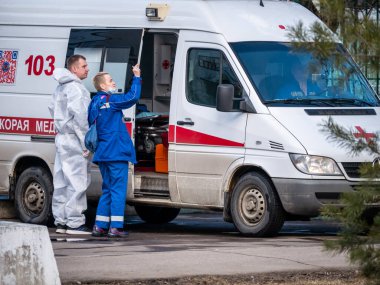 Rusya Moskova 2021 'de. Dört ambulans doktoru konuşuyor ve arabanın yanında duruyor.