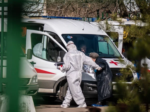 Rusya Moskova 2020. Paramedikler, enfeksiyon kapmış yaşlı bir adama ambulans arabasından enfeksiyon hastalıkları bölümüne, koronavirüse gitmesi için yardım ediyor..
