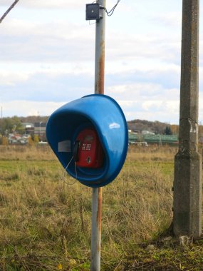 Yalnız, mavi bir telefon kulübesi bir tarlada duruyor.