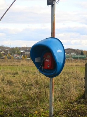Yalnız, mavi bir telefon kulübesi bir tarlada duruyor.