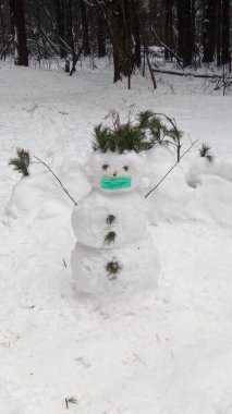 Yüzünde maske olan koronavirüs kardan adam.