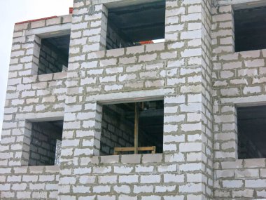 Üç katlı beyaz beton bina yapım aşamasında.