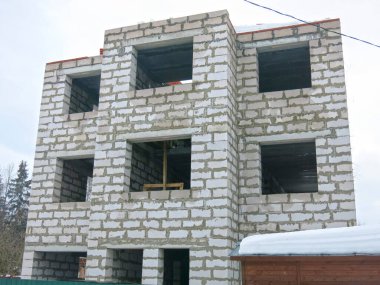 Üç katlı beyaz beton bina yapım aşamasında.