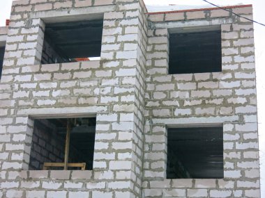 Üç katlı beyaz beton bina yapım aşamasında.