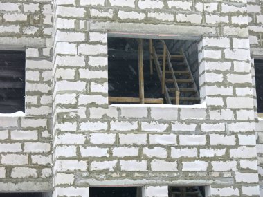 Üç katlı beyaz beton bina yapım aşamasında.