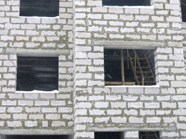 Üç katlı beyaz beton bina yapım aşamasında.