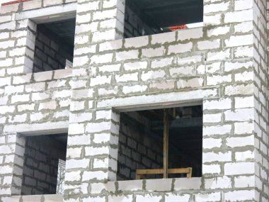 Üç katlı beyaz beton bina yapım aşamasında.