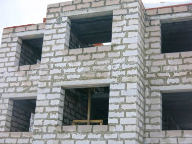 Üç katlı beyaz beton bina yapım aşamasında.