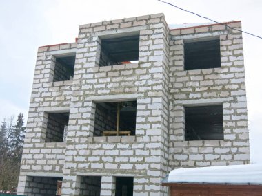 Üç katlı beyaz beton bina yapım aşamasında.