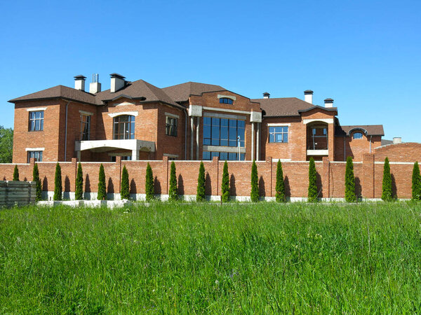 ландшафтный дизайн: ряды туи вдоль кирпичной стены коттеджа