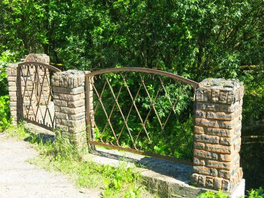 Yazın nehrin üzerinde dövülmüş demir kafesli eski bir köprü.