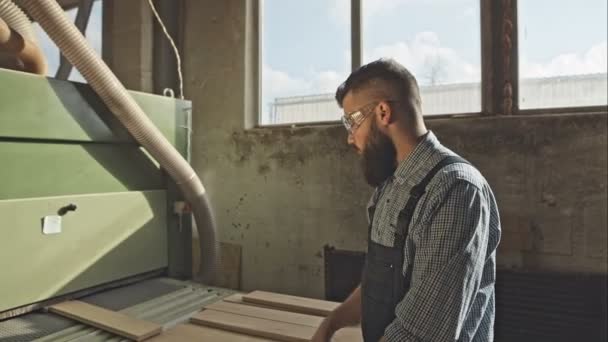 Człowiek pracy z wielkim elektryczne do kantów na produkcji deski podłogowe. Surowy zapis wideo. — Wideo stockowe