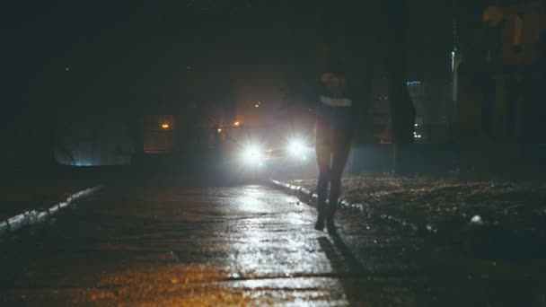 Chica de noche está en las peligrosas calles de la ciudad en los faros del coche . — Vídeo de stock