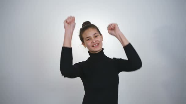 Porträtt av framgångsrik vinnare firar genom att dansa. Vacker ung glad kvinna isolerad på vit bakgrund. RAW vide orecord. — Stockvideo
