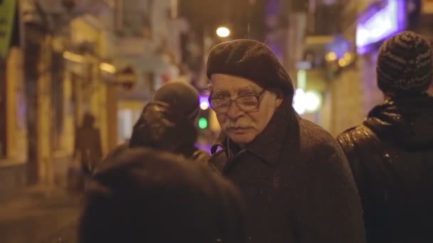 Il vecchio al centro dei giovani passanti per strada e la città non è niente sotto la pioggia. Scena emotiva e psicologica . — Video Stock