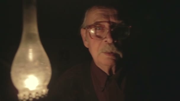 Das Gesicht des armen alten Großvaters mit einer Petroleumlampe in der Hand, der in der Nacht geht — Stockvideo