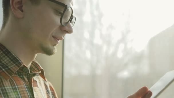 Homem sorridente usando tablet digital em um elevador de vidro - câmera lenta — Vídeo de Stock