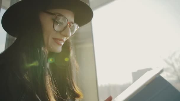 Chica en elevador de cristal en ascenso y feliz visualización de la información en una tableta - cámara lenta — Vídeo de stock