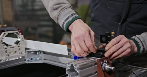 Mechanický montážní mechanismus v dílně. Nerozpoznatelný muž pracovník utahování šrouby při montáži mechanismu na pracovní stůl v profesionální garáži — Stock video