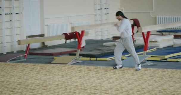 Giovane uomo atletico bello che è impegnato nelle corse sala fa colpi di scena del corpo e le mani intorno alla sala in abbigliamento sportivo si prepara per le competizioni importanti — Video Stock