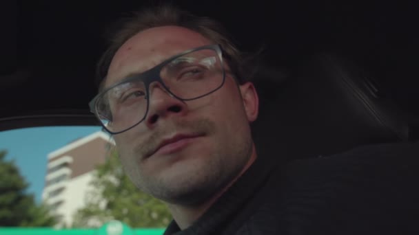 Homem desfavorecido com óculos senta-se em um carro e segura uma arma em suas mãos. O homem está a planear um suicídio ou homicídio num carro.. — Vídeo de Stock