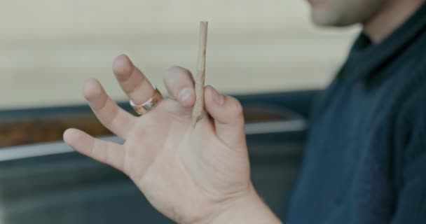 Cigarrillo de cannabis en la mano de un hombre mayor sentado en un coche. El concepto de drogas ligeras — Vídeo de stock