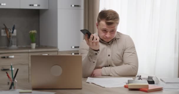 Een man die thuis aan een bureau zit, houdt een telefoon vast... heeft een onaangename dialoog, nerveuze ruzies... conflicten en gooit de telefoon weg. — Stockvideo