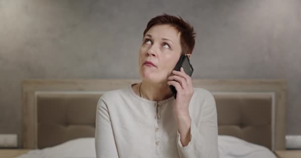 Donna matura infastidito parlando su smartphone. Insoddisfatta di mezza età femmina guardando altrove e ascoltando l'avversario mentre litigava sul cellulare a casa — Video Stock